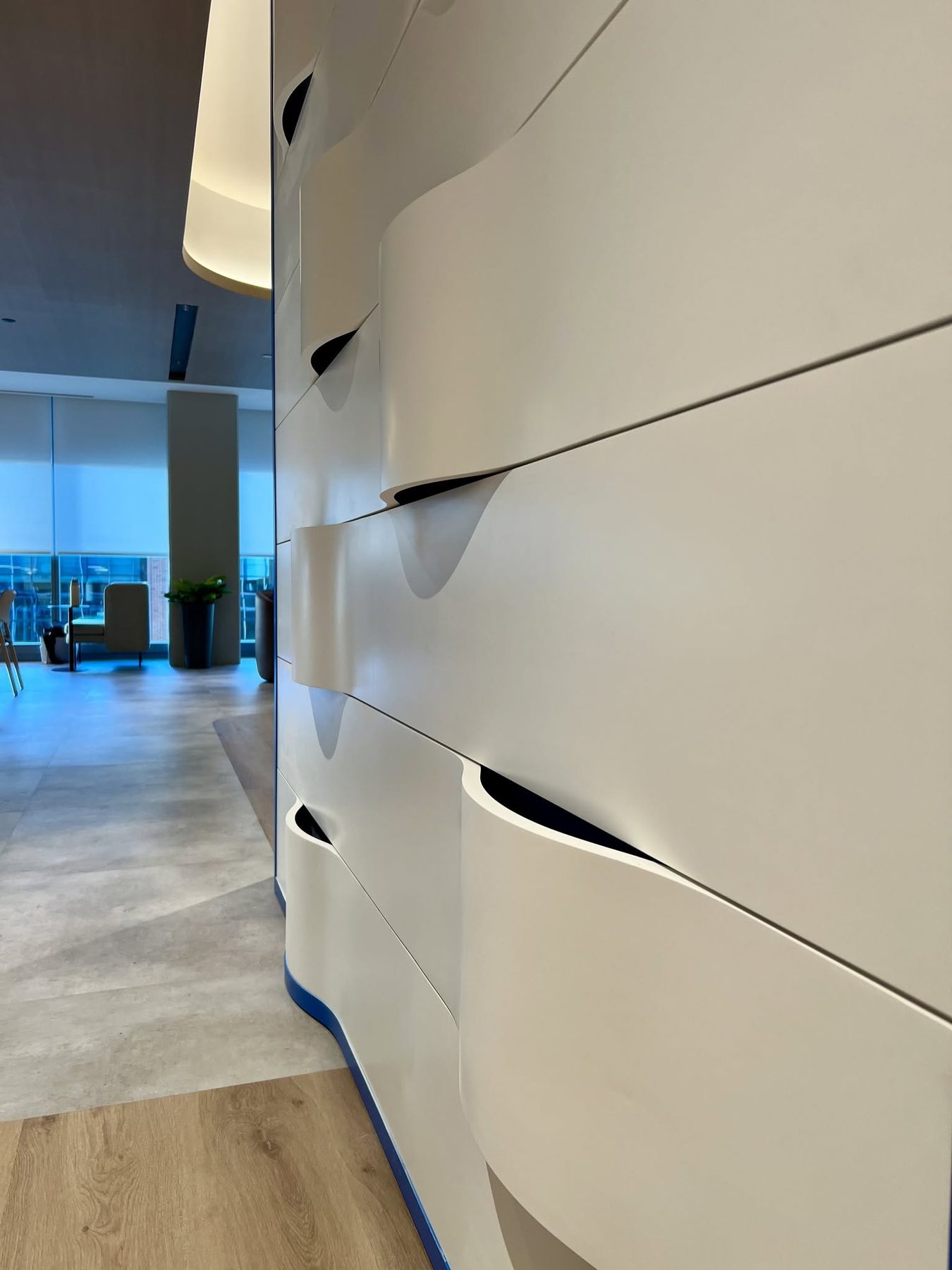 White painted CNC relief wall with wave pockets in an office corridor